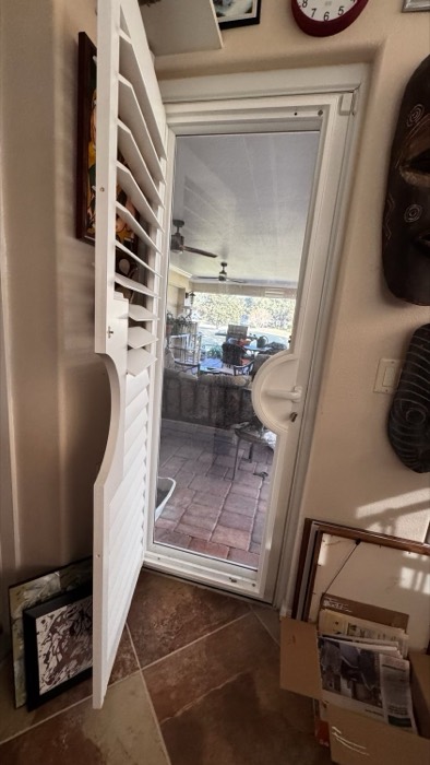 Plantation shutter on a back door, open to a patio
