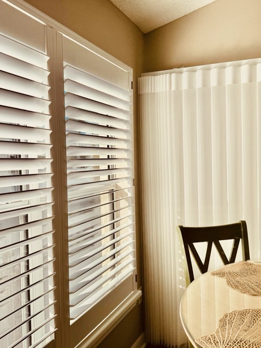 Plantation shutters paired with wave sheer drapery in a corner room