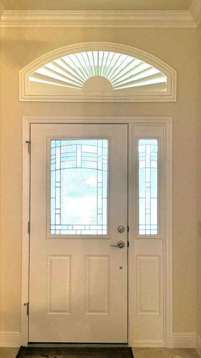 Sunburst arch plantation shutter above a stained-glass front entry door